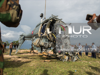 Cambodian people look at a damaged helicopter after it crashed on the outskirts of Phnom Penh on 14, July 2014. According to offical, Four C...