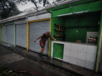 A woman rushes to save her goods inside her small stall in Manila as Typhoon Glenda, international name Rammasun, pummels through the city o...