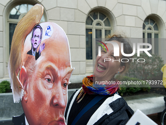 Artist Carla Krash holds a Trump-protest sign that includes a moving hairpiece as she joins a small group of protestors outside US Customs a...