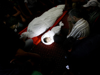 Palestinian mourners gather around the body of five-month-old Fares al-Mahmum and another victim of Israeli bombardment during their funeral...