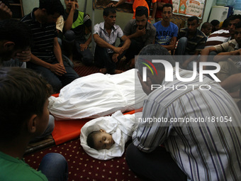 Palestinian mourners gather around the body of five-month-old Fares al-Mahmum and another victim of Israeli bombardment during their funeral...