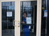 Women smiles as she stands behind a closed door of a bank as Philadelphia Fire Department responds to a PECO Substation fire, on March 7th,...