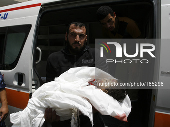 A Palestinian man carries the body of Dalal Siam, a five-month-old child who was killed along with eight members of the Siam family after an...