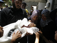 A Palestinian man carries the body of Dalal Siam, a five-month-old child who was killed along with eight members of the Siam family after an...