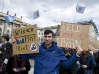 A man attending the 'March for Science' holds banners reading 'science isn't silence' and 'feed your brain' in Berlin, Germany on April 22,...