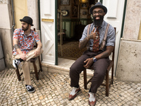 Two young men pose in front of their hairdressing business on a centric street in the historical center of Lisbon (Portugal)
 (