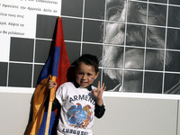 A boy with the Armenian flag in front of a photograph of the American Armenian novelist William Saroyan, at Syntagma square, in central Athe...