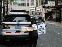 A protester stands behind a police care with signs demanding the release of and support for Mumia Abu-Jamal in Philadelphia, PA on April 24,...