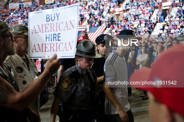 State troopers escort an unidentified protester, while on the side members of 