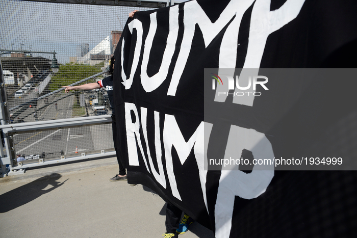Protesters carry a banner that reads DUMP TRUMP, as they cross the pedestrian bridge that leads towards the USS Intrepid, in New York City,...