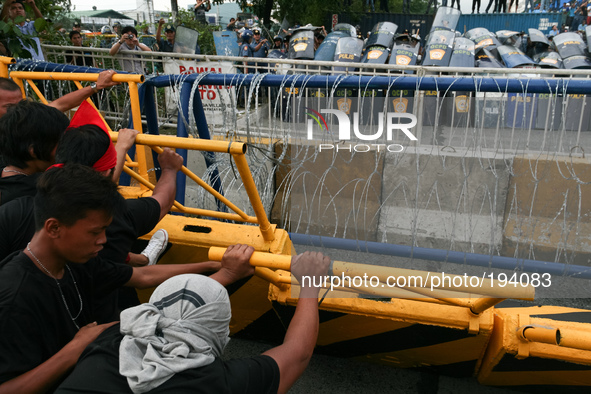 Protesters trying to pull down concrete barriers along Commonwealth Avenue in Quezon City as the police readies in formation. Thousands of p...