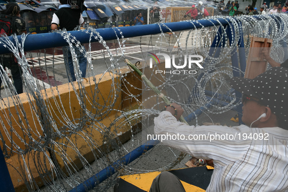 A protester trying to make a hole around the concertina razor wires. Thousands of protesters rallied at the same time as President Aquino ga...