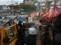 Protesters try to topple the razor wire barrier as they are pummeled by high pressure water cannons. Thousands of protesters rallied at the...
