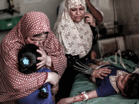 A Palestinian woman along with her wounded daughter who was injured in an air israeli strike, on July 28, 2014, in Gaza. A strike in a publi...