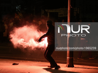 A protestor throws a flare to police officers outside the Greek Parliament on May 18, 2018. Young protesters clashed with riot police during...