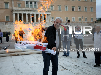 A man sets Syriza’s flag on fire during an anti-austerity demonstration during the voting on new austerity measures in Athens, Greece, May 1...