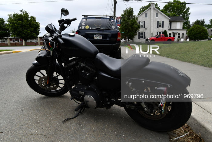 Matt black Harley Davidson, a dark-collared SUV and a red pick-up parked on a residential street in QuarryVile, PA, on May 20, 2017. A Risin...