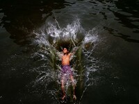 Local boys jumps into the water of a pond for cool to beat the heat the afternoon in the eastern Indian state Odisha's capital city Bhubanes...