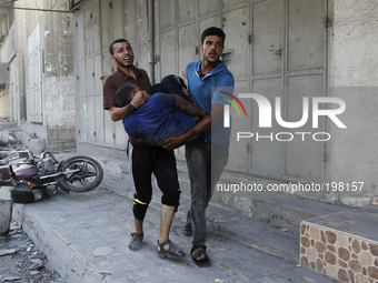 Palestinians carry a man who was wounded during an Israeli airstrike in the Shejaiya neighbourhood east of Gaza City, on 30 July 2014. Israe...