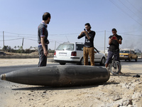 Palestinian men taken picture beside an unexploded Israeli shell that landed on the side of a road in Deir al-Balah, central Gaza Strip, on...