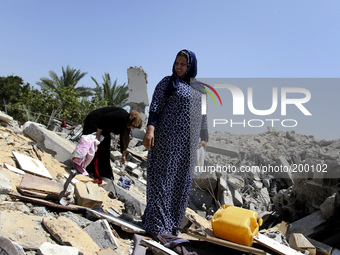 Palestinian women inspect a destroyed of their house in the Bureij refugee camp in the central Gaza Strip on 01 August 2014. (
