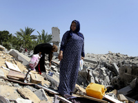 Palestinian women inspect a destroyed of their house in the Bureij refugee camp in the central Gaza Strip on 01 August 2014. (