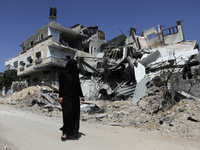 A Palestinian woman walks in front of a destroyed house in the Bureij refugee camp in the central Gaza Strip on 01 August 2014. (