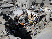Palestinians search for bodies at the rubble of the destroyed house for the Al-Bayoumi family in the al-Nusairat refugee camp in the central...