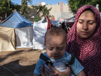 A mother holding her baby at the refugee camp set up behind the Al-Shifaa Hospital. Lack of nutrients and access to clean water might worsen...