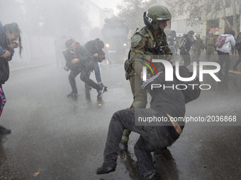 A protester is arrested under water thrown by water cannon cars.
Led by the Confederation of Chilean Students (CONFECH), the march for univ...