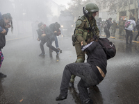 A protester is arrested under water thrown by water cannon cars.
Led by the Confederation of Chilean Students (CONFECH), the march for univ...