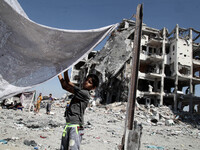 Palestinian boy to prepare a tent in front of residential buildings badly damaged after returning from the town of Beit Lahiya  as the fragi...