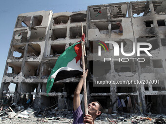 Palestinians raise the Palestinian flag in front of residential buildings badly damaged after returning from the town of Beit Lahiya   as th...