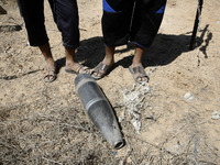 Palestinians look at the Projectile fired from an Israeli fly earlier in Rafah in the southern Gaza Strip, on August 6, 2014, while Israeli...