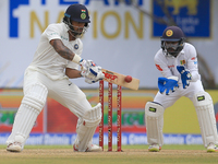 Indian cricketer Shikhar Dhawan(L) plays a shot during the 1st Day's play in the 1st Test match between Sri Lanka and India at the Galle Int...
