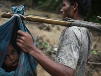  A Rohingya child is carried on a sling while his family walk through hill after crossing the border into Bangladesh near Cox's Bazar's Tekn...