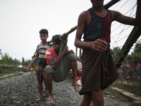 Rohinga people carry a man in a sack and walk through the border net to cross at Mongdaw, Myanmar. September 6, 2017  Rohingya are a Muslim...