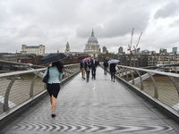 People are seen walking on Millennium Bridge holding umbrellas, due to the heavy rain, London on September 8, 2017.  (