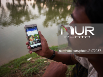 A Rohingya ethnic minority man looking facebook at his cell phone at a temporary makeshift camp after crossing over from Myanmar into the Ba...