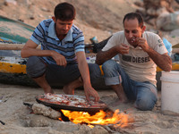 Palestinians cooking crabs on Gaza beach in the Shati refugee camp in Gaza City on September 10, 2017. (