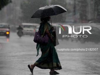 Pedestrians and commuters look on road in a sudden downpour time in the eastern Indian state Odisha's capital city Bhubaneswar on 13 Septemb...