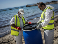 Municipal workers along with volunteers try to contain the oil spill from the Greek tanker Agia Zoni II,  which sank off the island of Salam...