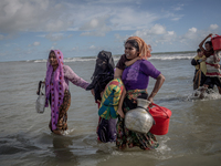 Rohingya refugee women walk to the shore of Bangladesh after crossing the Naf river by boat. Shahpirer Dip, Teknaf, Bangladesh; September 14...