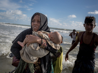 A Rohingya mother with her two months old child walks to the shore after crossing the Naf river by boat. Shahpirer Dip, Teknaf, Bangladesh;...