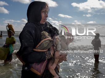A Rohingya mother cries, holding her two months old child and walks to the shore after crossing the Naf River by boat. Shahpirer Dip, Teknaf...