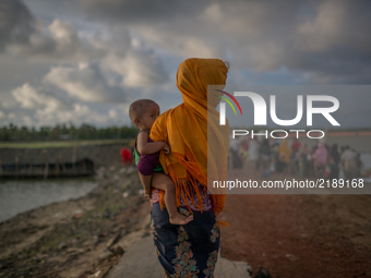 A Rohingya refugee mother with her child entering Bangladesh. Shahpirer Dip, Teknaf, Bangladesh; September 14, 2017. Bangladesh will use tro...