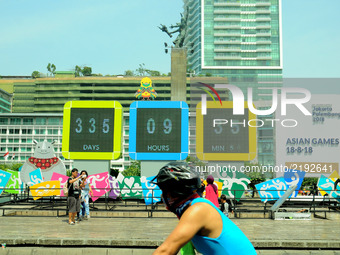 Jakarta residents take pictures in front of the screen countdown the implementation of Asian games installed in the park roundabout monument...