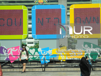Jakarta residents take pictures in front of the screen countdown the implementation of Asian games installed in the park roundabout monument...
