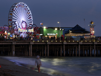 People enjoy the beach as the sun sets on Santa Monica Pier in Santa Monica, California on September 16, 2017. (
