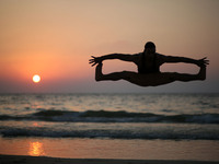 A Palestinian youth jumps on the beach as the sun sets over Gaza City on 18 September 2017.
 (